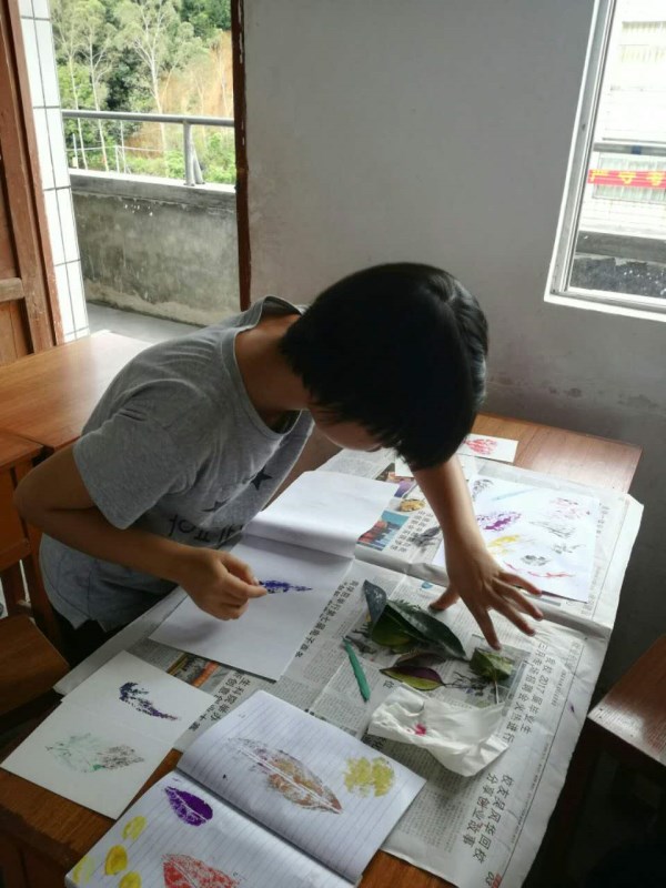 一位学生在认认真真制作树叶明信片